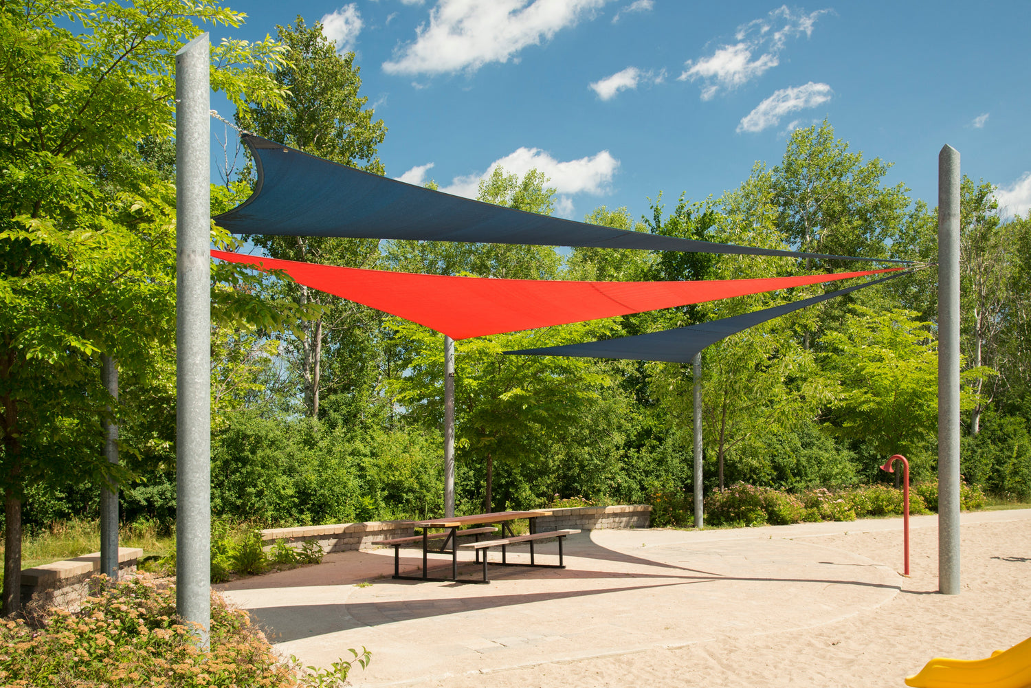blue and orange shade sail attached in a beach area showcasing shade for pickleball shade solutions