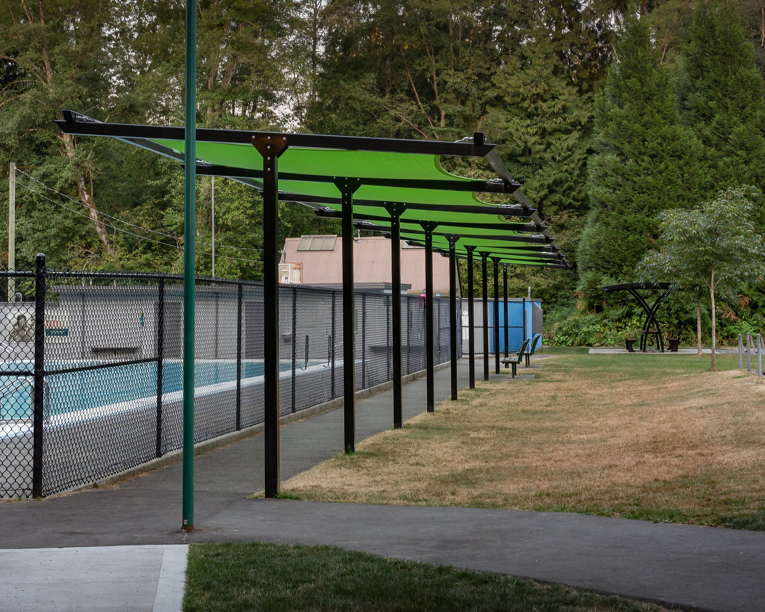image of a public pool and green shade sail over pool.