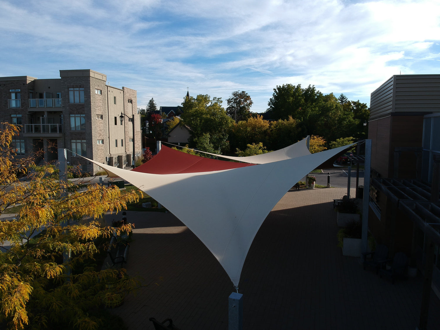 Modern white and red sailcloth shade installation in an urban courtyard, showing how design and shade work together in creating private outdoor retreats with shade sails.