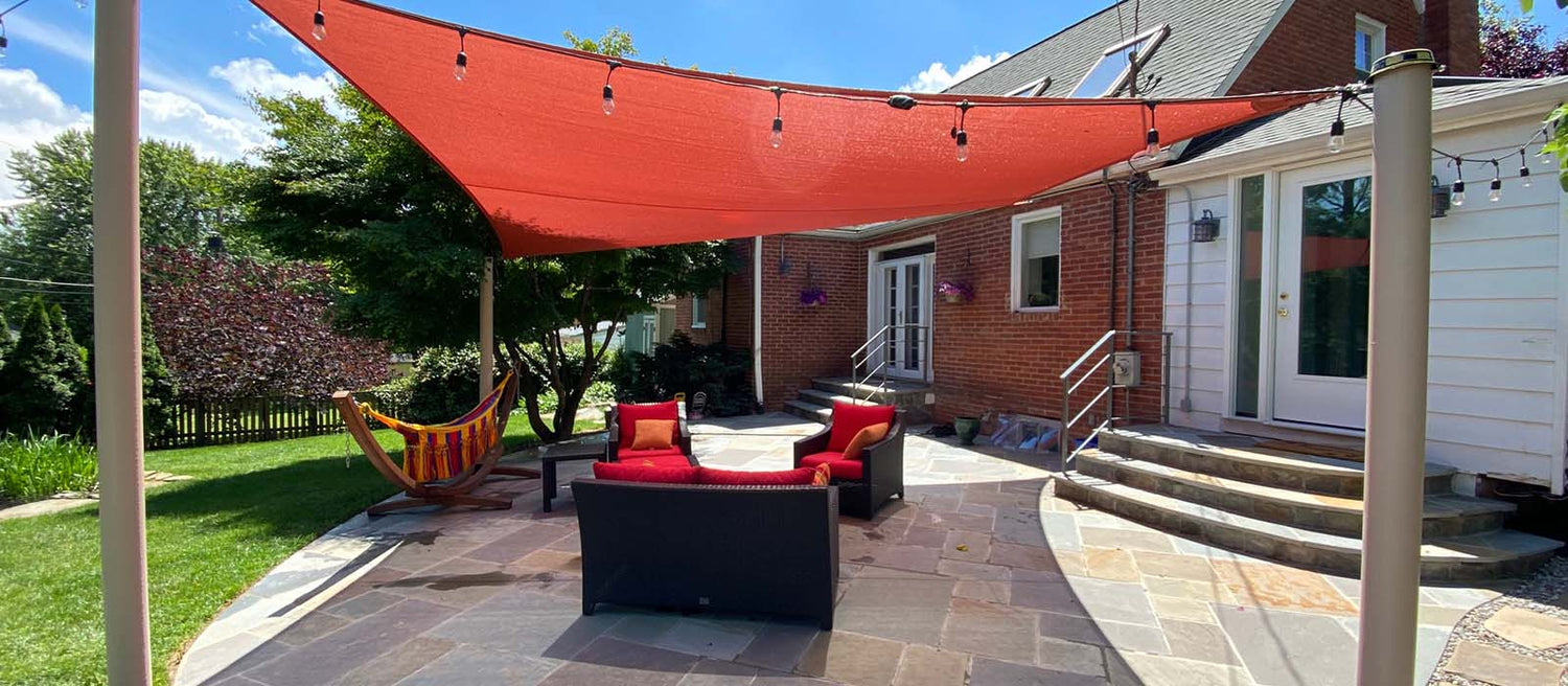 A bold terracotta shade sail demonstrates how to shade a patio while adding warmth and vibrancy to your backyard seating area.
