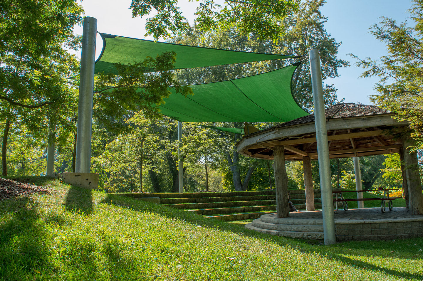Green shade sails installed over an outdoor classroom amphitheatre in Toronto Island Park, providing sun protection and enhancing the natural learning environment.