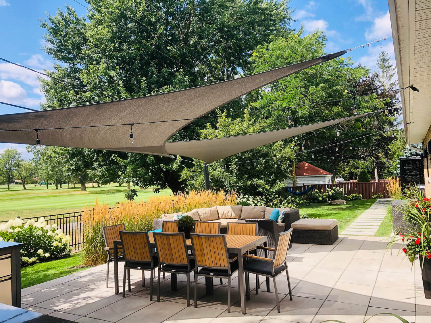 dining table and chairs on a backyard patio shade sails overtop providing outdoor dining shade