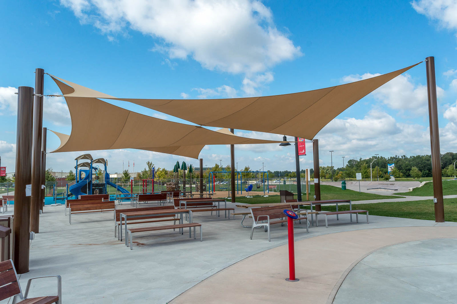 beige shade sails over a playground in a school yard providing shade for children