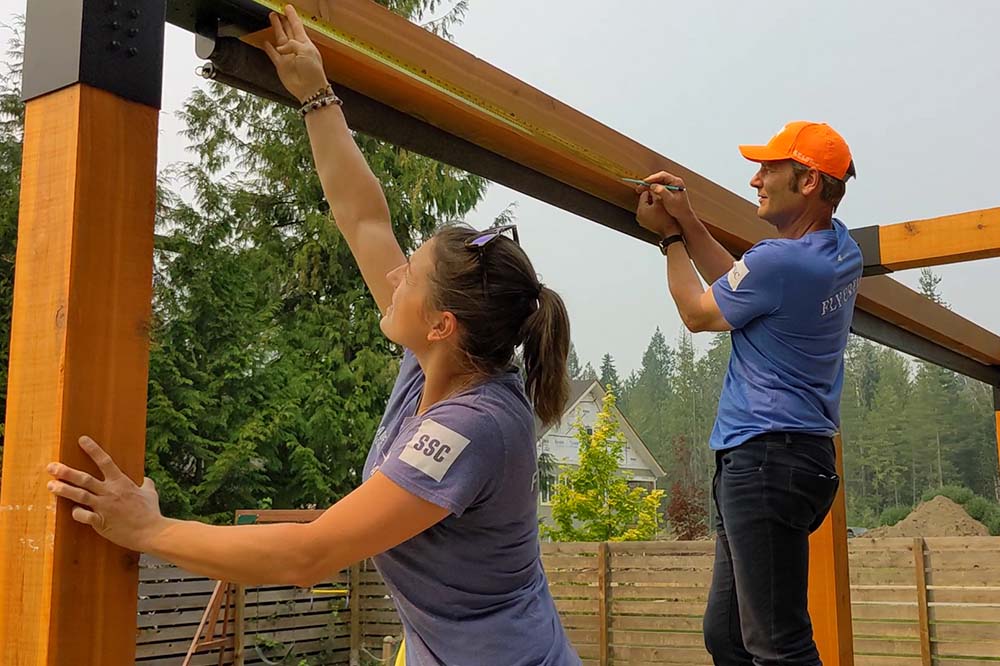 a man and women working hard and putting together a durable tensile structure.