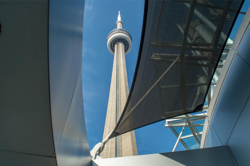 Black shade sail installation at the Metro Toronto Convention Centre, with the CN Tower in the background.