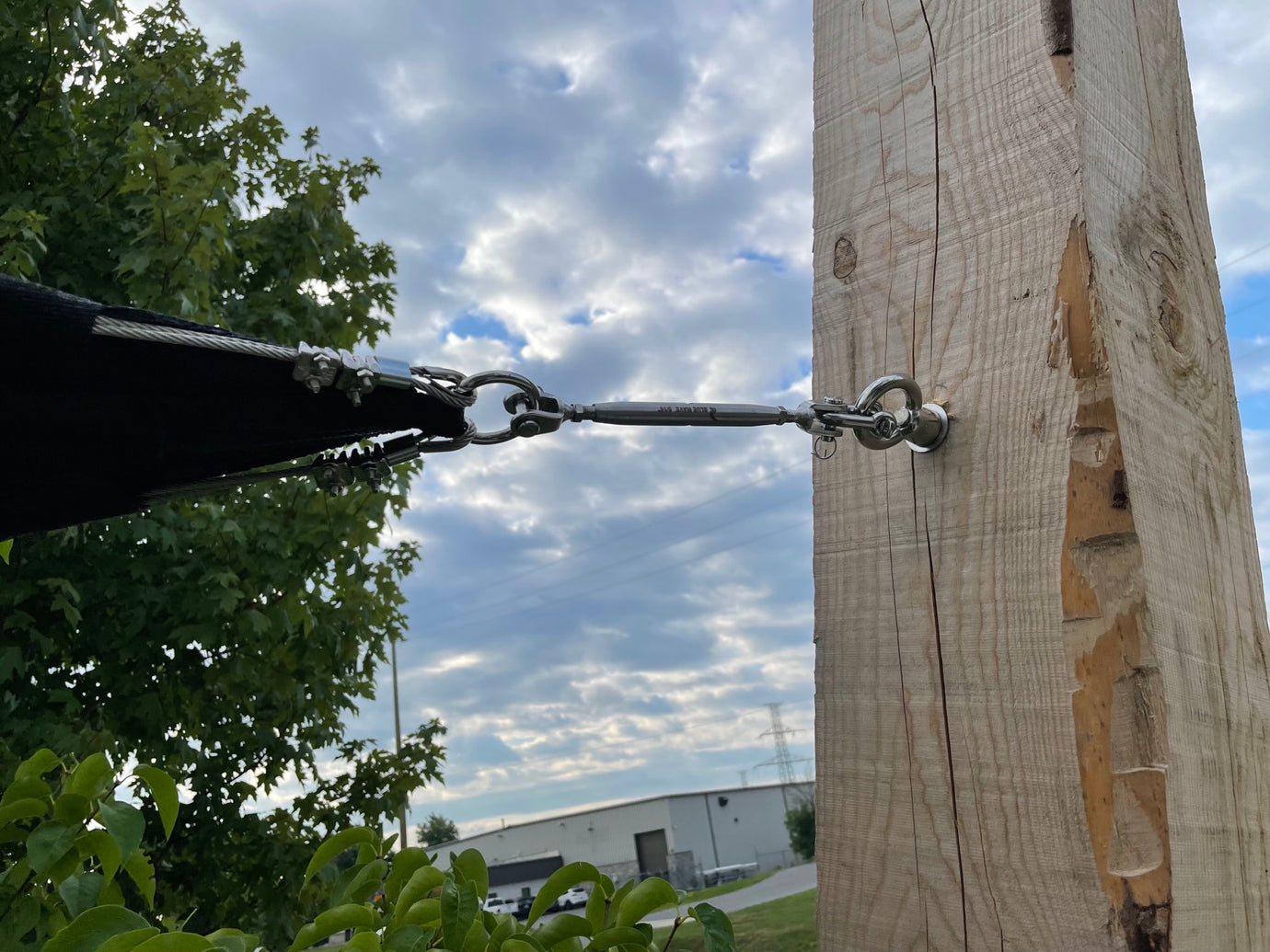 closeup image showing tension shade sails attached to a wooden pole on a sunny day.