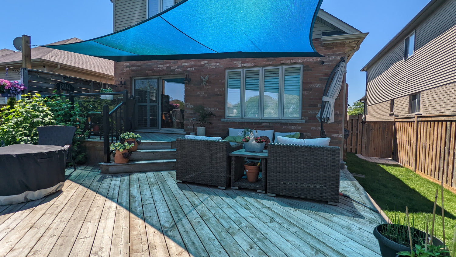 Cozy backyard deck with comfortable seating and a large blue diy shade sail offering shade and relaxation.