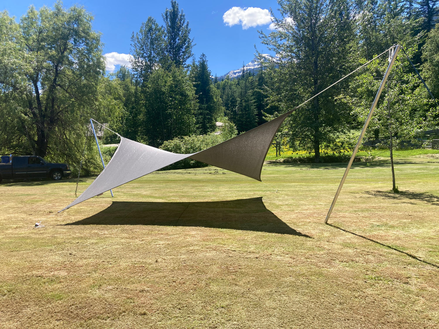 image of grey shade sail on the grass with forestry in the background.