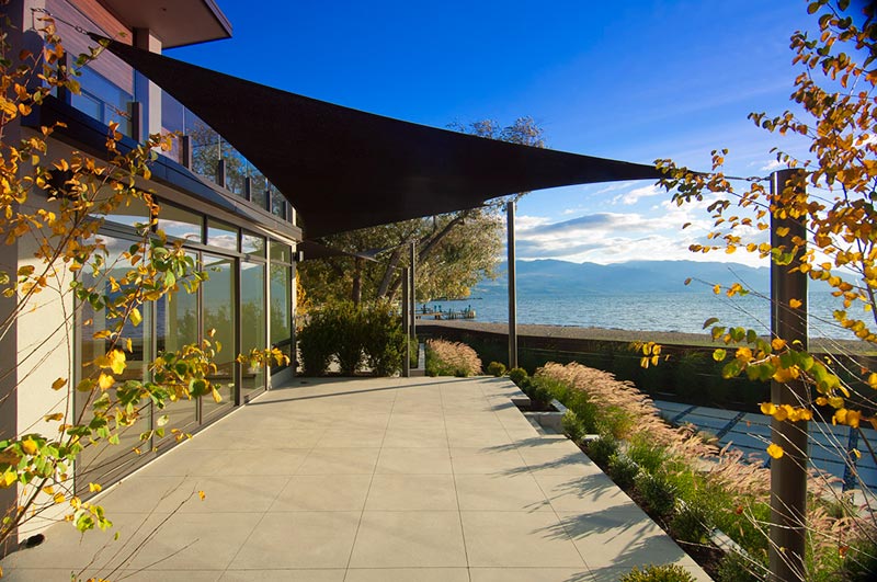 black triangular shade sail over a patio with a sunny view