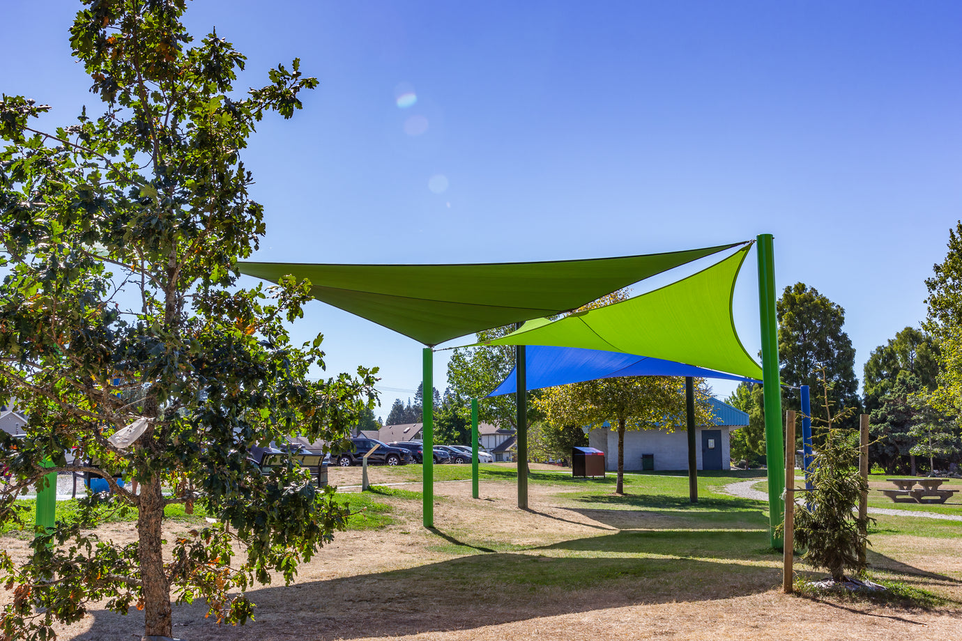 two shade sails at a park providing weather protection on a sunny day.