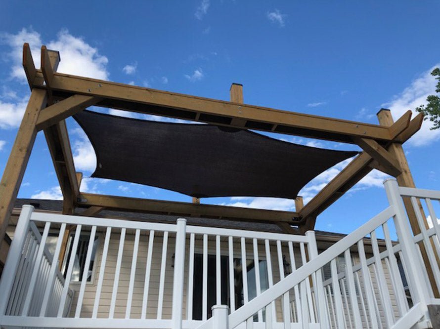 black sun shade over a deck providing uv protection
