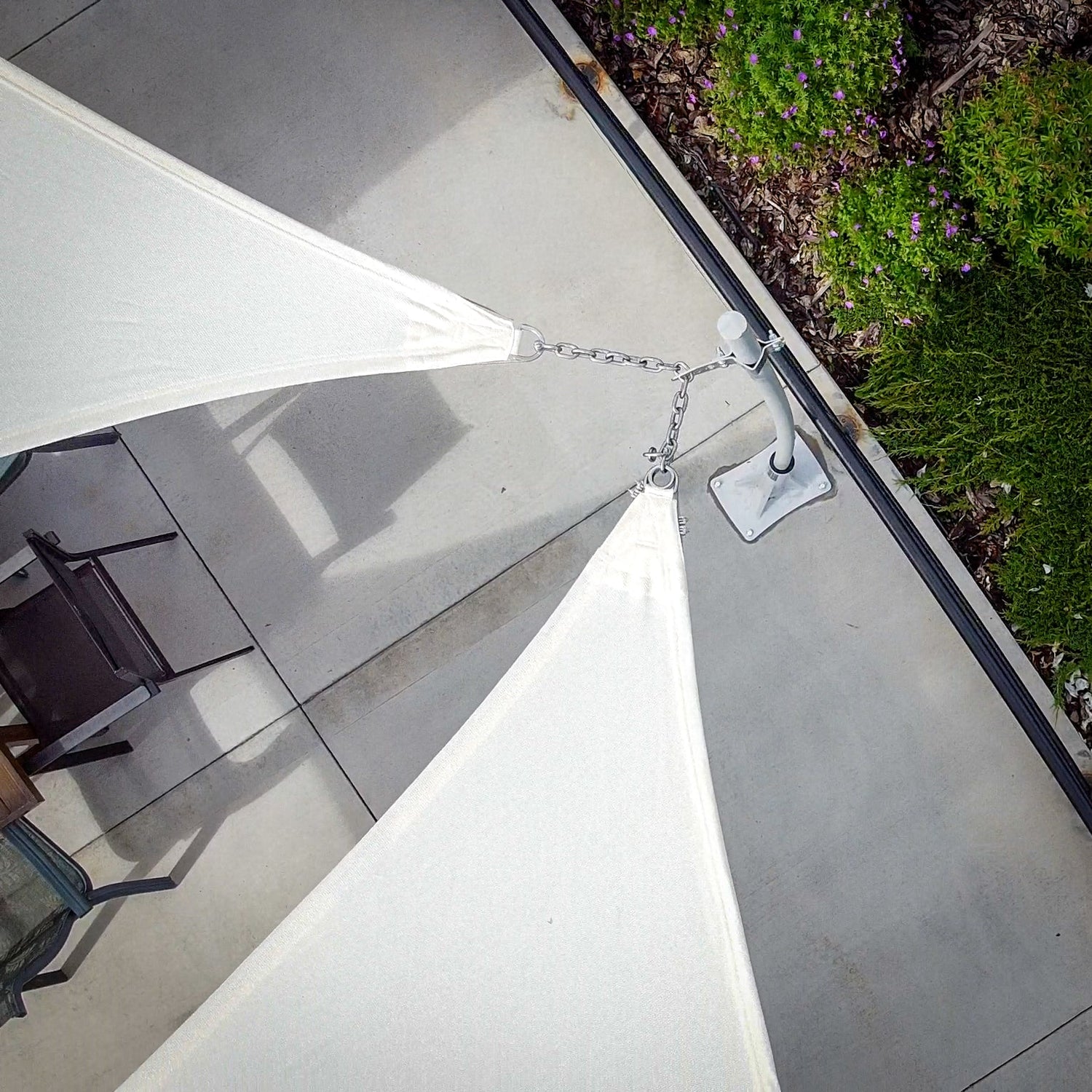 Close-up of Shade Sail Mounting Hardware with chain and anchor point securing fabric to metal post on patio