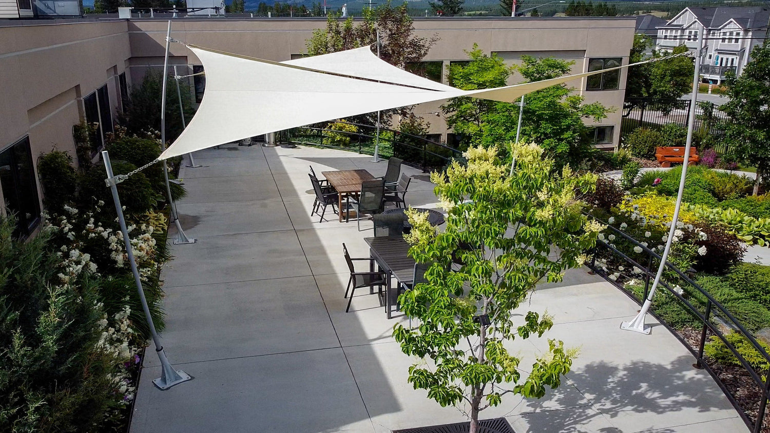 Modern courtyard patio featuring white tensile Custom Exterior Sun Shades installed above outdoor seating for stylish UV protection.