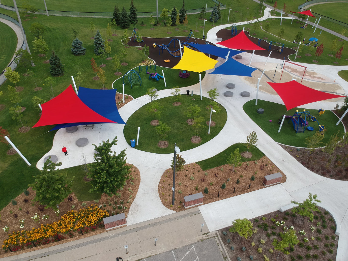 aerial view of red, blue and yellow shade sails over a well-landscaped property providing shade structures for schools