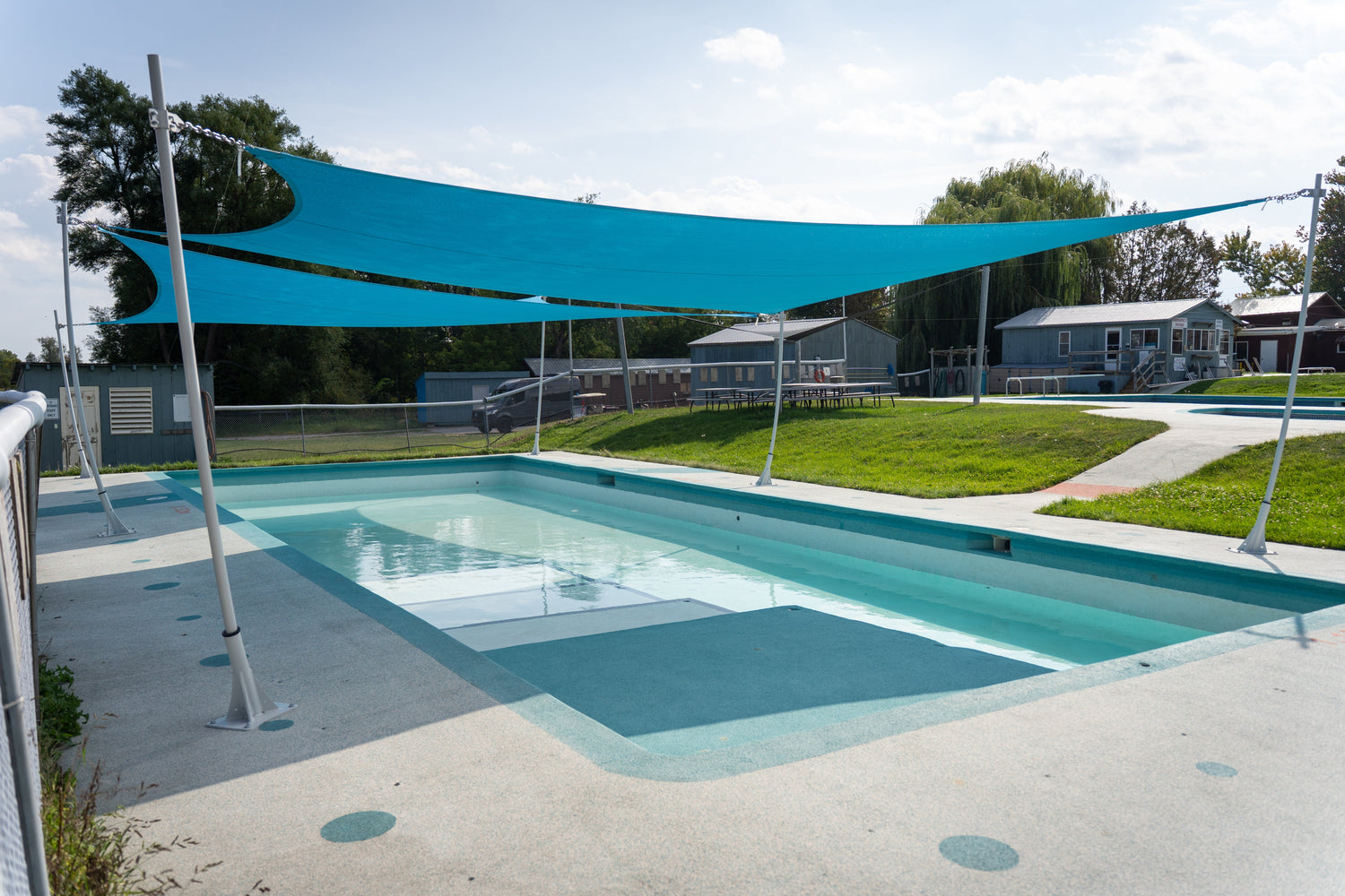 Shade for pools using blue shade sails to provide sun protection over a shallow swimming area.