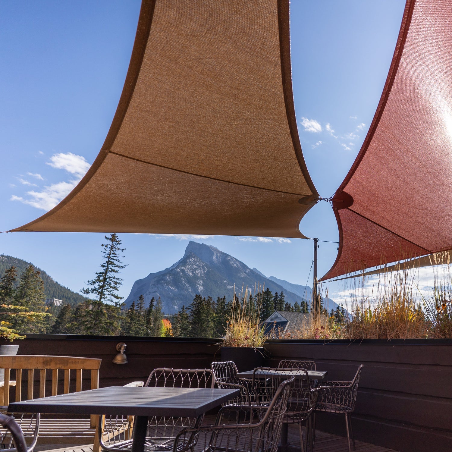 Heavy duty outdoor shades installed over a restaurant patio, providing durable sun protection with a scenic mountain backdrop.