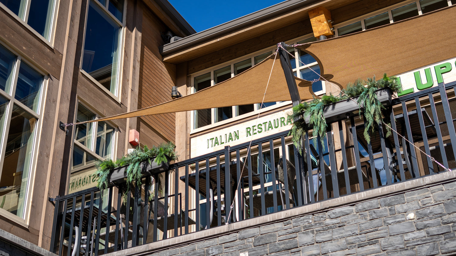 Exterior Sun Blocking Shades mounted above a second-story restaurant balcony, delivering sun protection while maintaining an open, architectural look.
