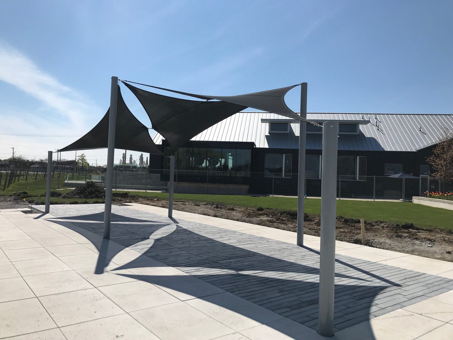 Modern outdoor walkway covered by sleek Sunshades and Canopies, providing architectural shade and comfort near a commercial building.