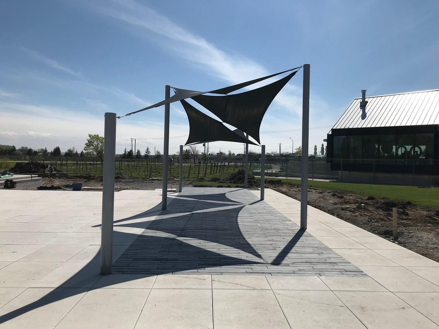 Modern outdoor structure with stretched Shade Material Fabric panels providing UV protection and architectural shade in a landscaped area.