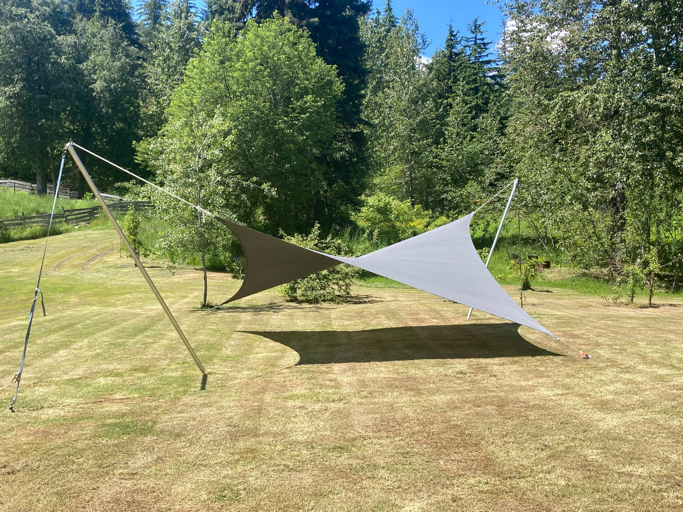 Modern triangular breathable shade sails installed over grassy backyard providing sun protection and airflow