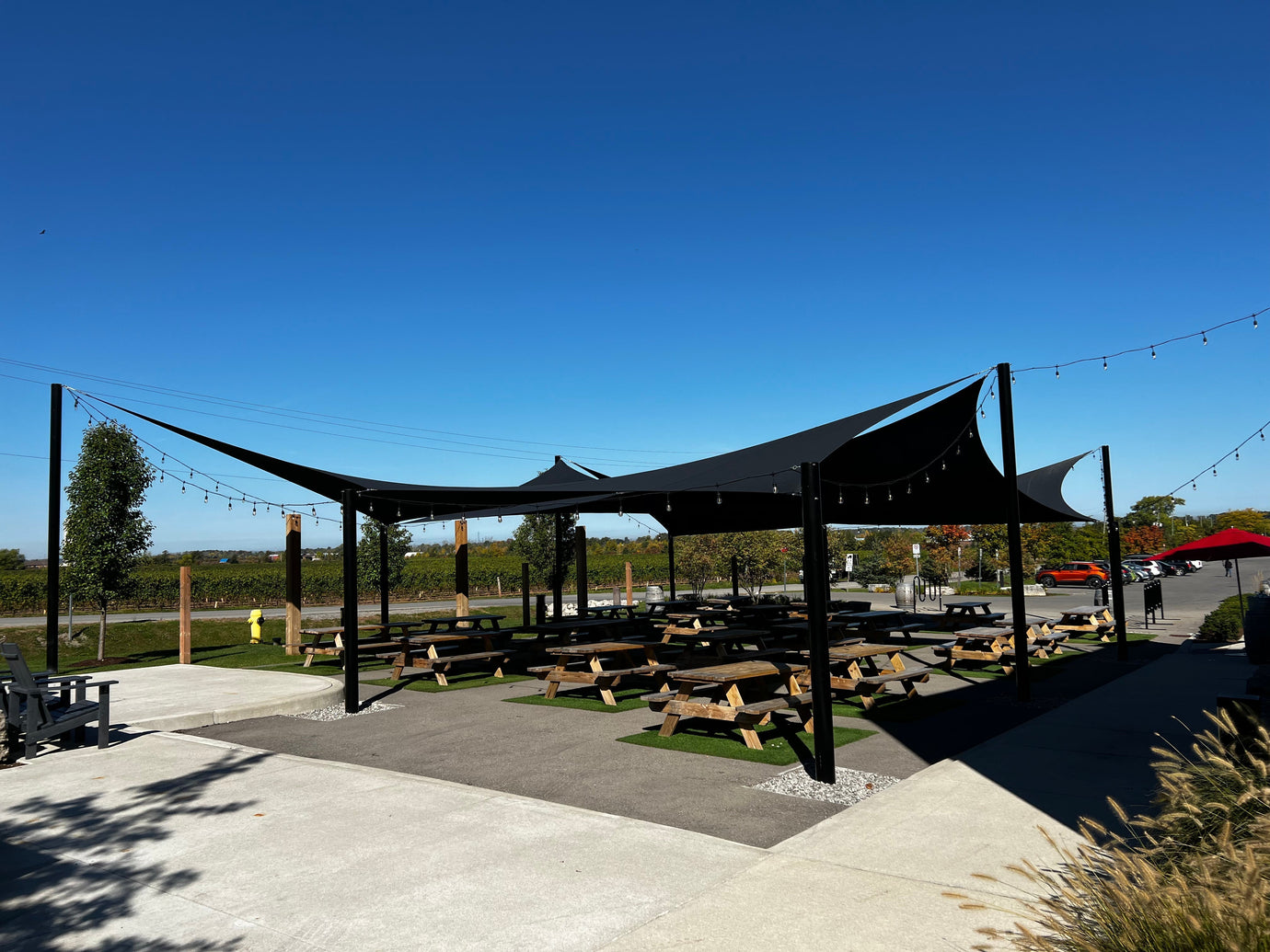 Black shade sails covering a concrete patio with picnic tables underneath