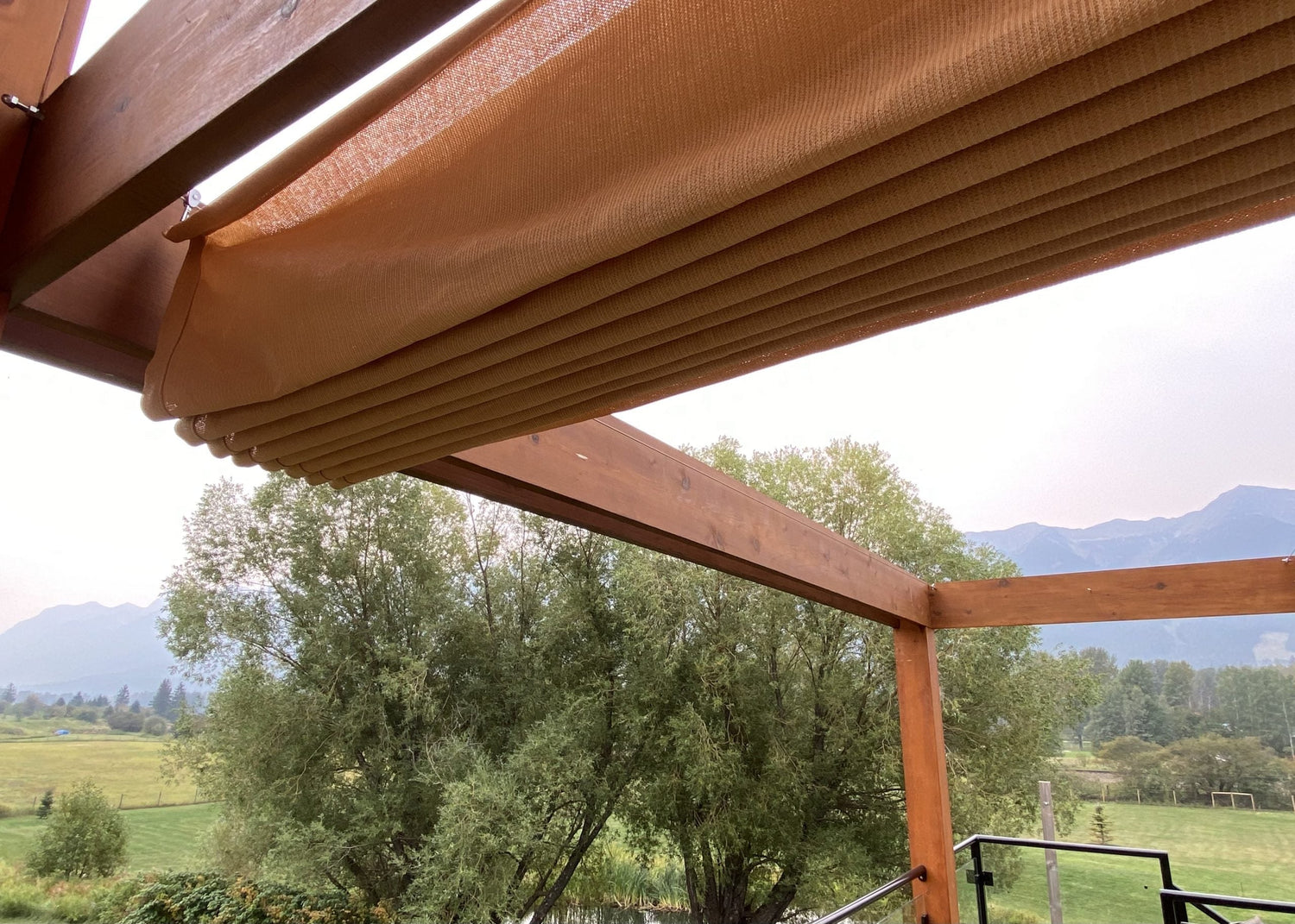 Retractable shade canopy on a wooden pergola overlooking scenic mountains, showcasing creative and affordable backyard designs for outdoor comfort.