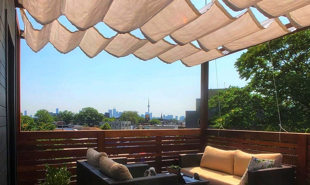Rooftop deck with a soft fabric canopy stretched above cozy wicker furniture, showing how motorized patio canopies can glide open or closed to control shade with ease.
