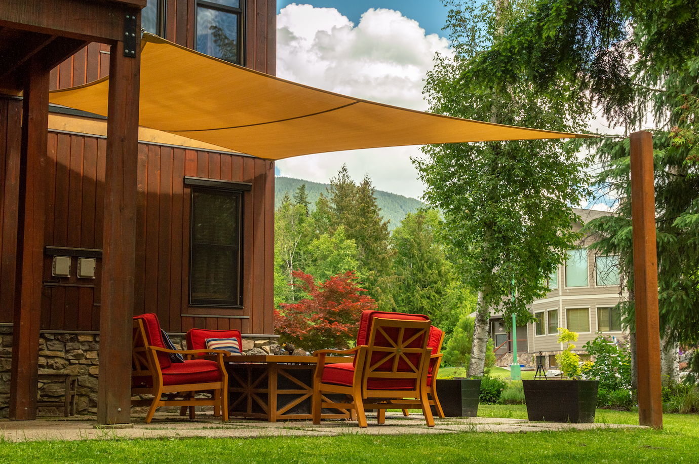 orange shade sail in backyard providing patio shade solutions over a backyard patio set