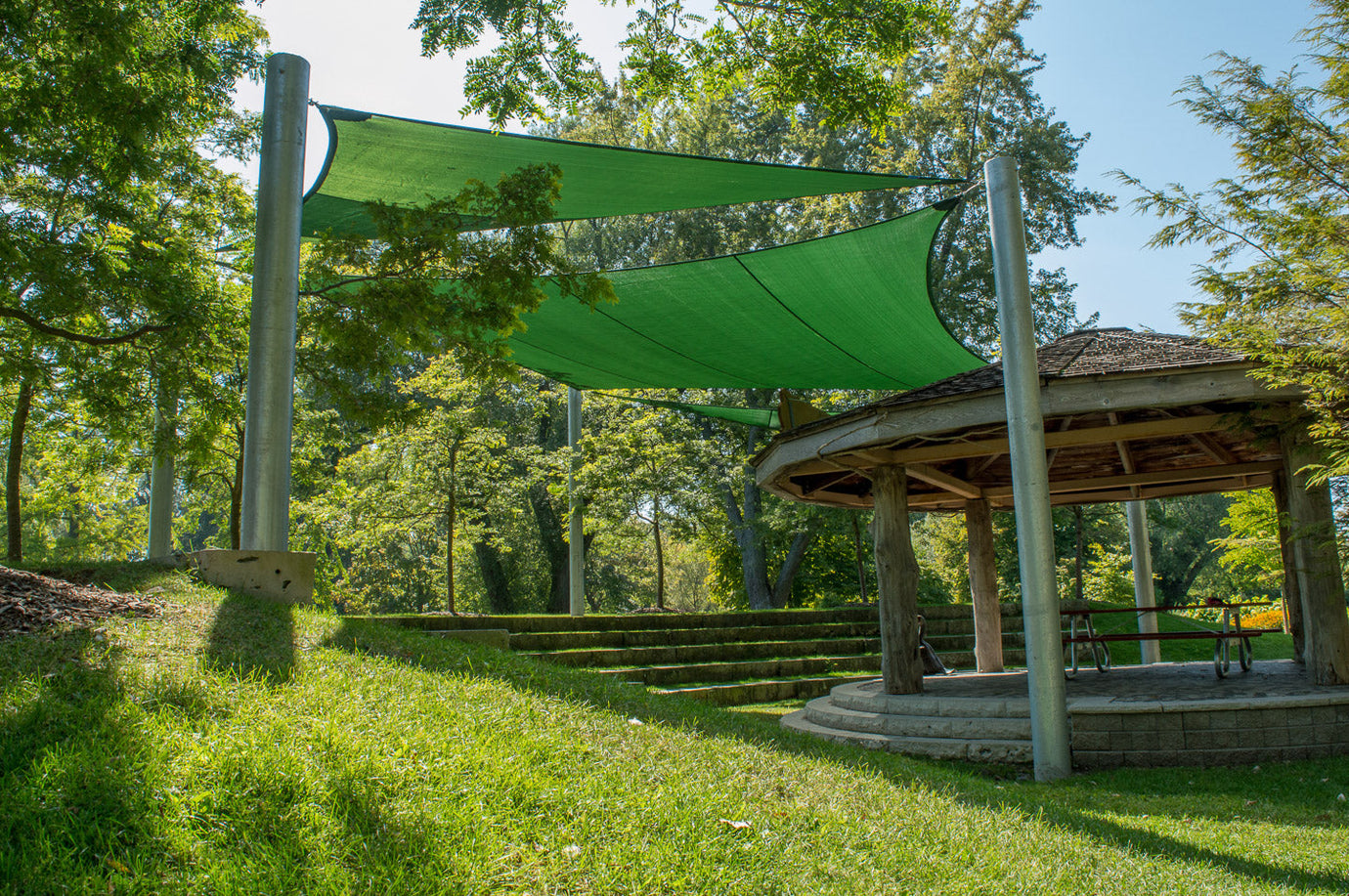 Green shade sails installed over an outdoor classroom amphitheatre in Toronto Island Park, providing sun protection and enhancing the natural learning environment.