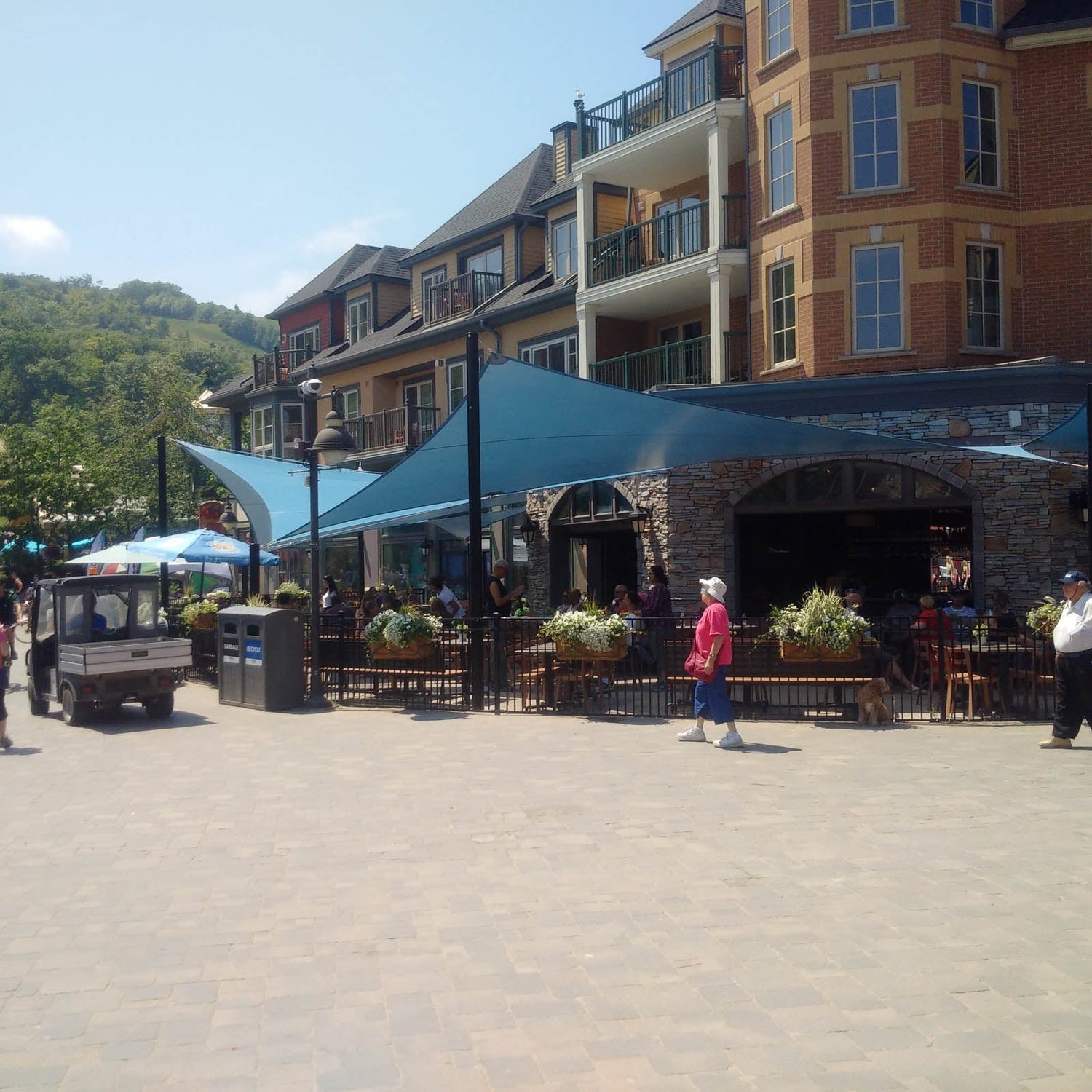 blue shade sails over a large commercial patio in a downtown area