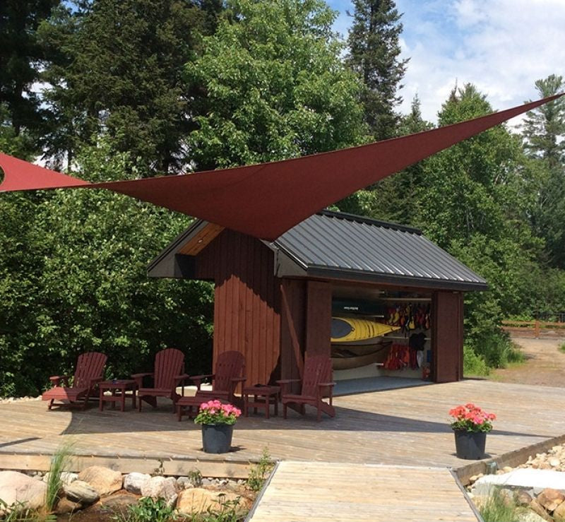 red triangular shade sail over a large backyard patio