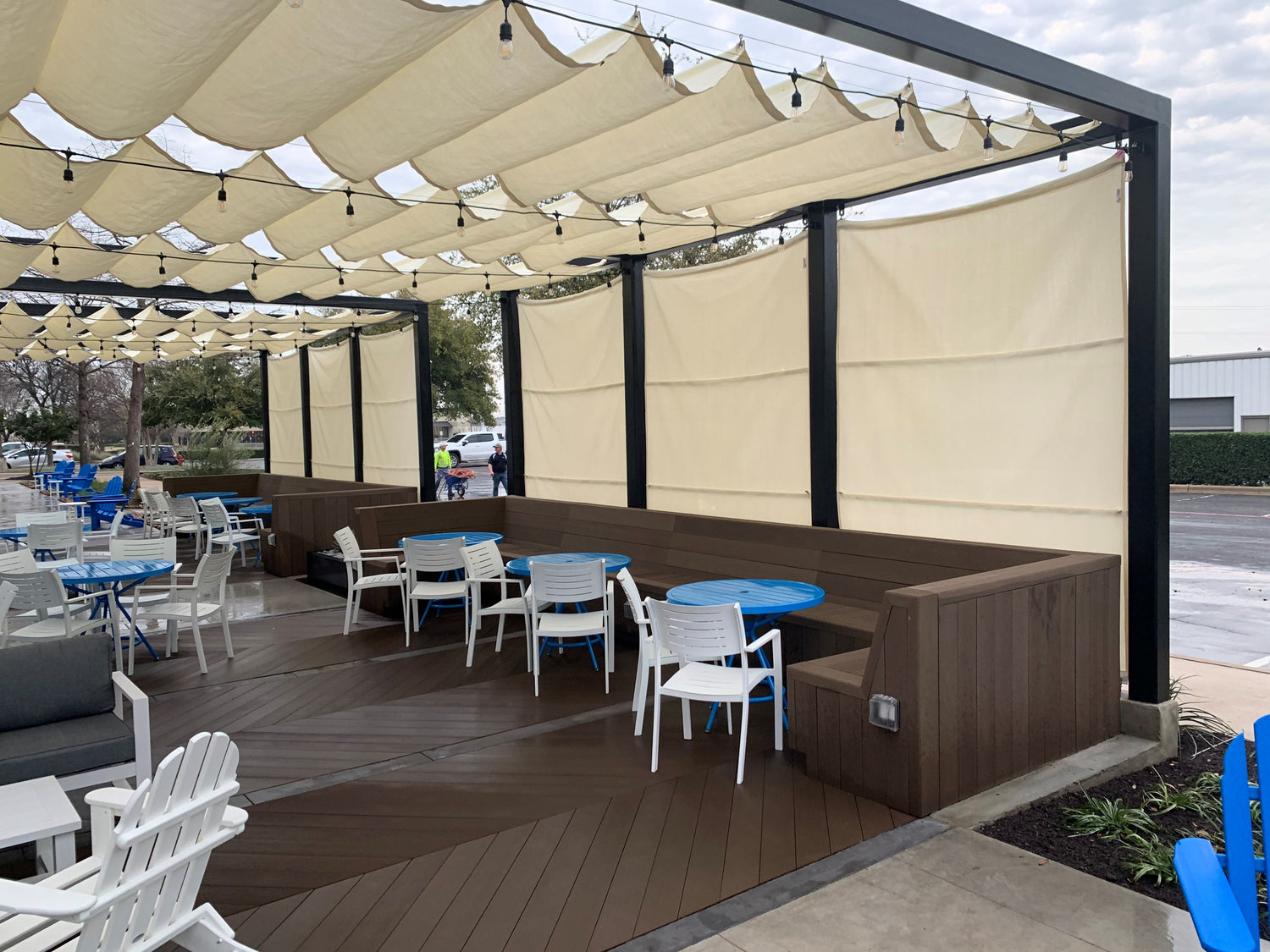 Shaded dark brown deck with multiple tables and chairs, featuring a pergola retractable  overhead.