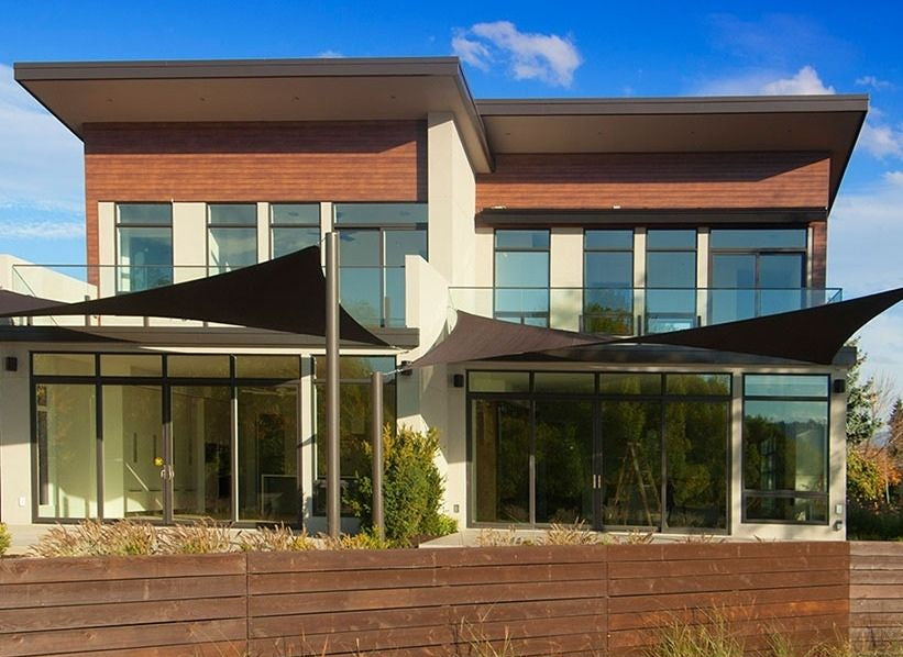 Contemporary home exterior featuring multiple black shade sails, visually answering the question Are Shade Sails Waterproof through functional, elegant design.
