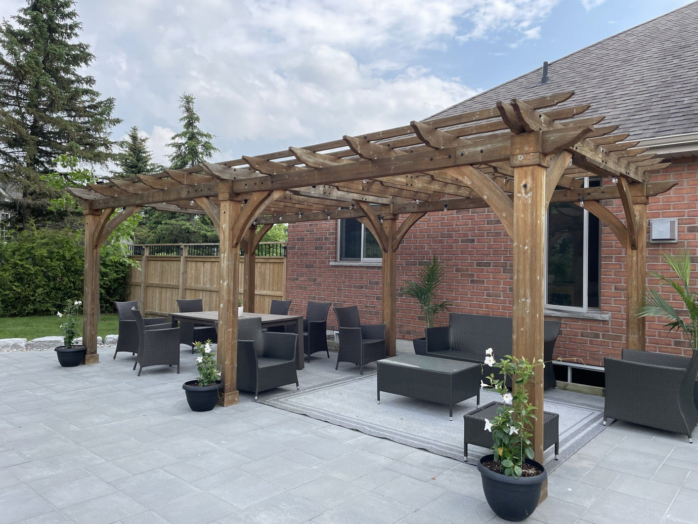 large stone patio with black patio furniture under a pergola, representing patio design ideas