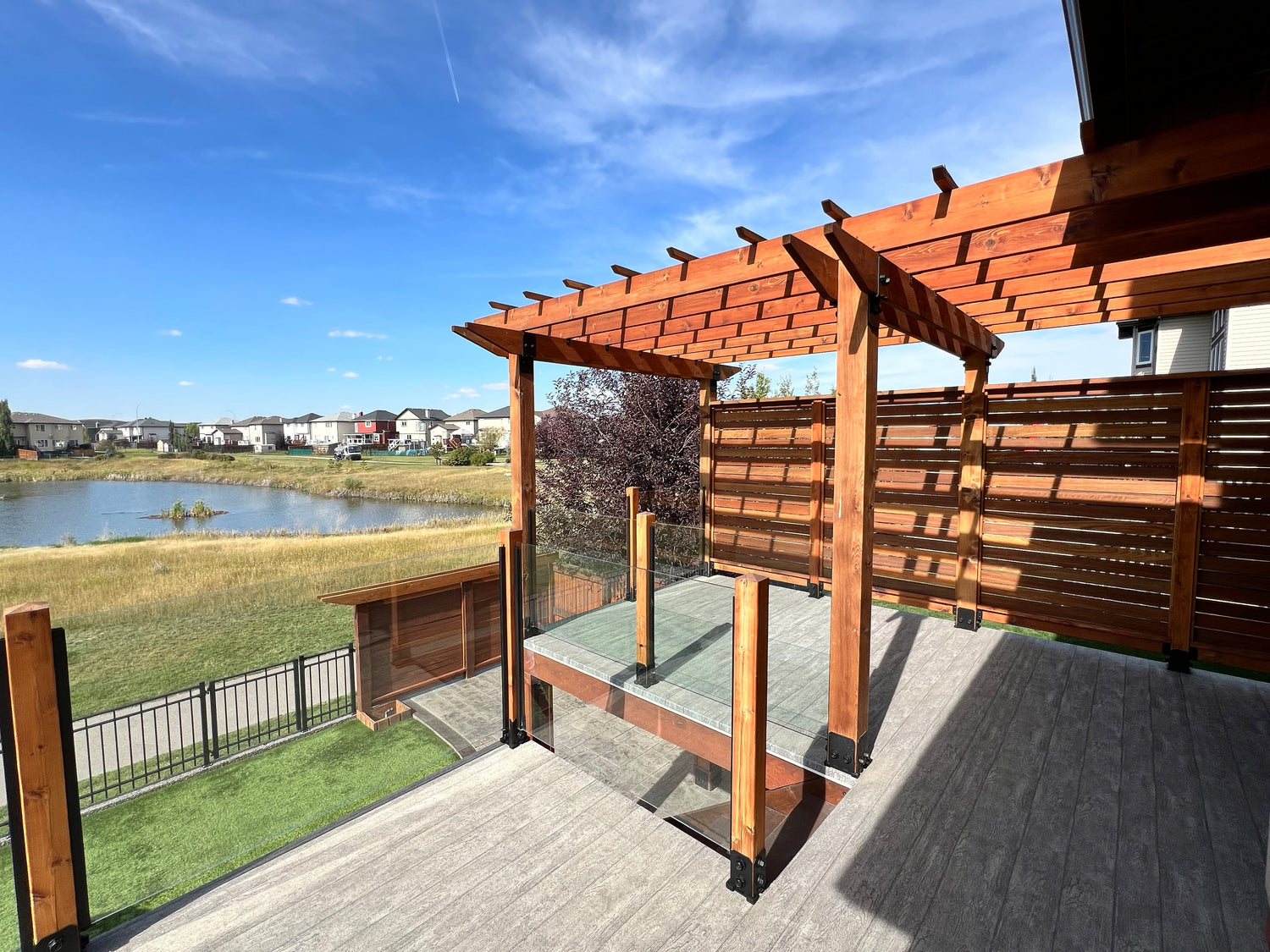 custom shade sails pergola in a backyard facing a large pond