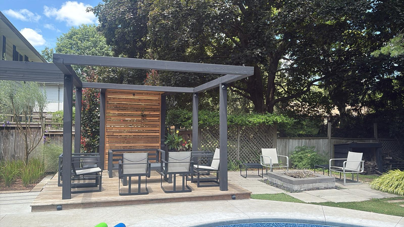 Contemporary pergola lounge with seating and modern outdoor lanterns adding ambient lighting to a landscaped backyard.