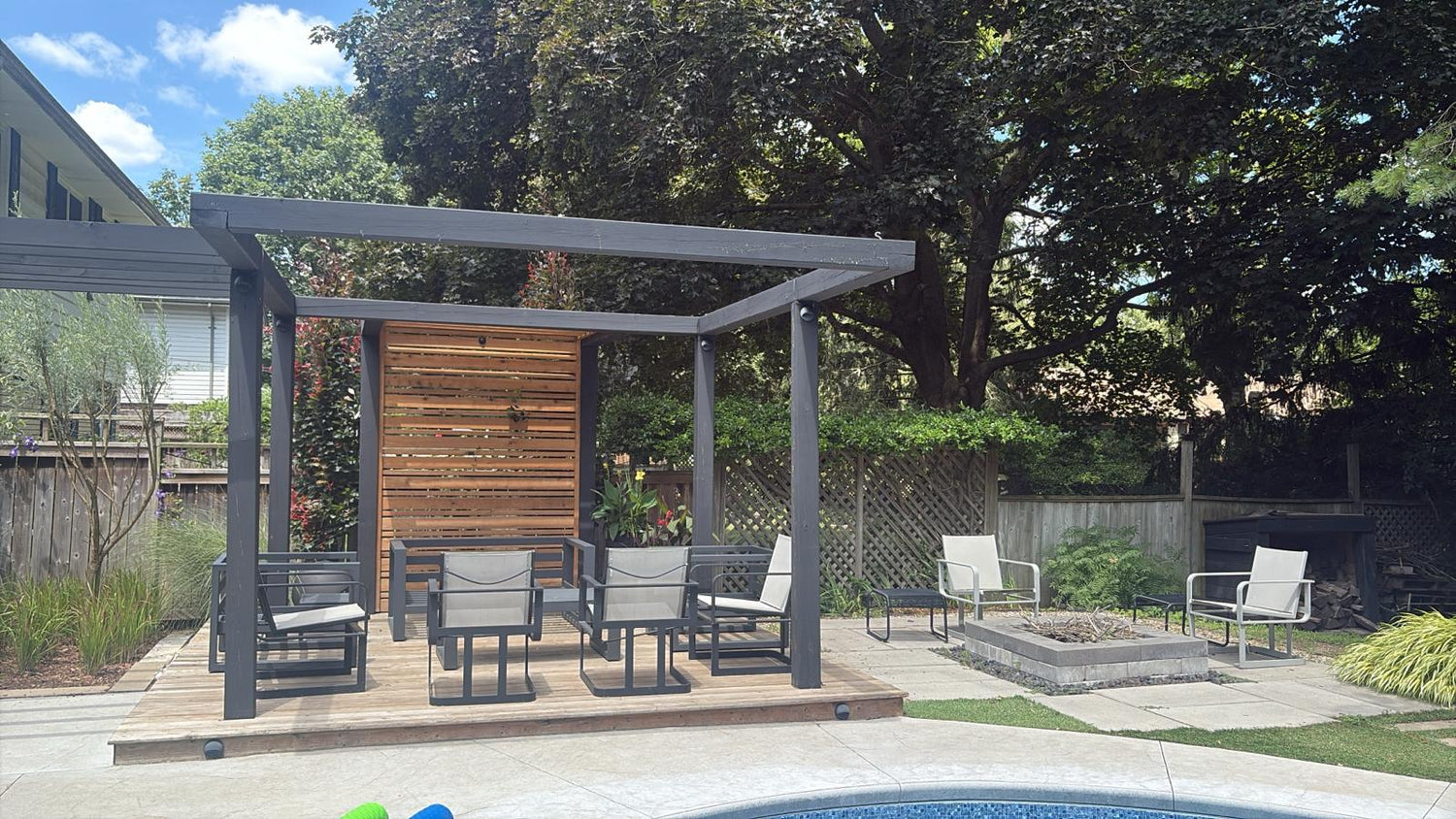 Contemporary pergola lounge with seating and modern outdoor lanterns adding ambient lighting to a landscaped backyard.