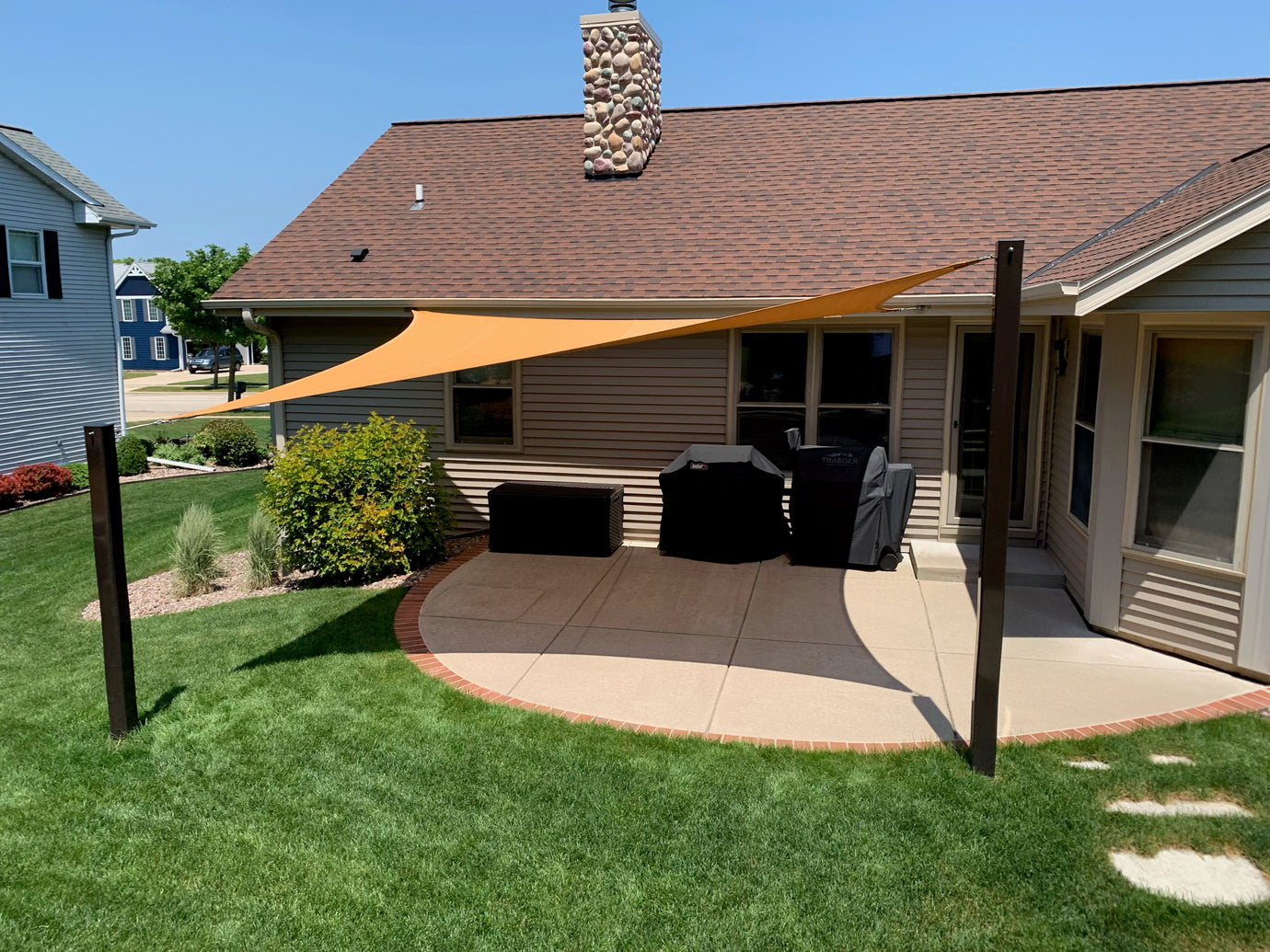 image of orange shade sail in backyard showcasing strength of shade sail wall plates with anchors.