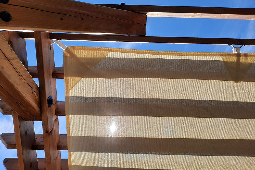 beige pergola shade attached with the light shining on it, showcasing shades for animals.  
