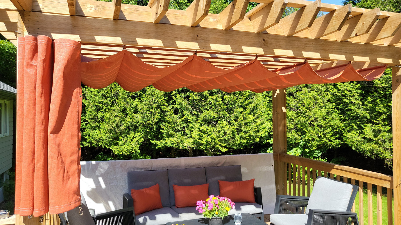 A cozy outdoor seating area under a wooden pergola with orange fabric shades providing a stylish and practical shade solution.