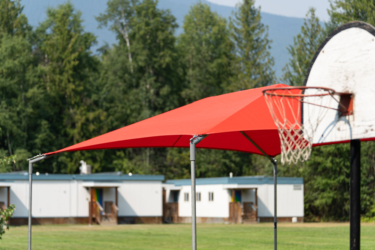 A red outdoor basketball canopy shade structure supported by silver metal poles,